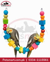 Two cockails perched on a colorful wooden bird toy made of hanging blocks and beads, photographed against a white background with Petsmart branding and contact details.