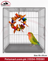A gray metal pet cage with a hanging wooden toy and a small green-and-pink bird standing inside, shown on a white background with Petsmart branding and size text.