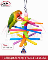 A colorful wooden parrot toy with radiating sticks and a hanging bell, shown with a green and peach parrot perched on it. The image includes a Petsmart logo, size information, and contact details on a white background.